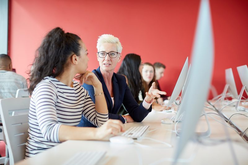 Colleagues working together at computers in a training room